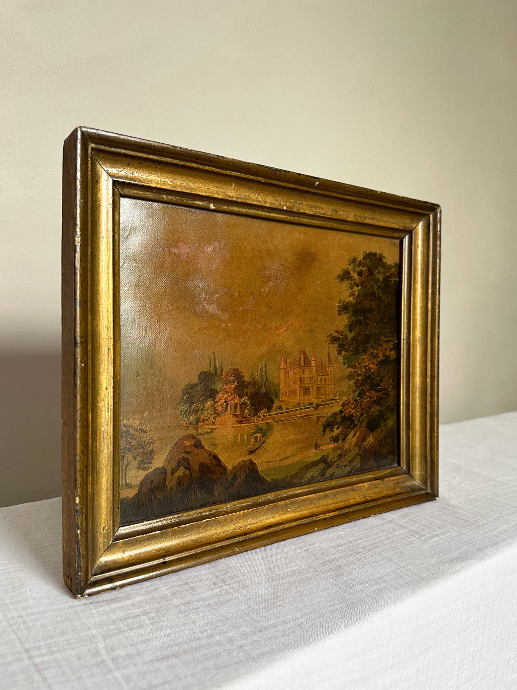 an antique oil painting in a gilt wood frame, of a french chateau and landscape
