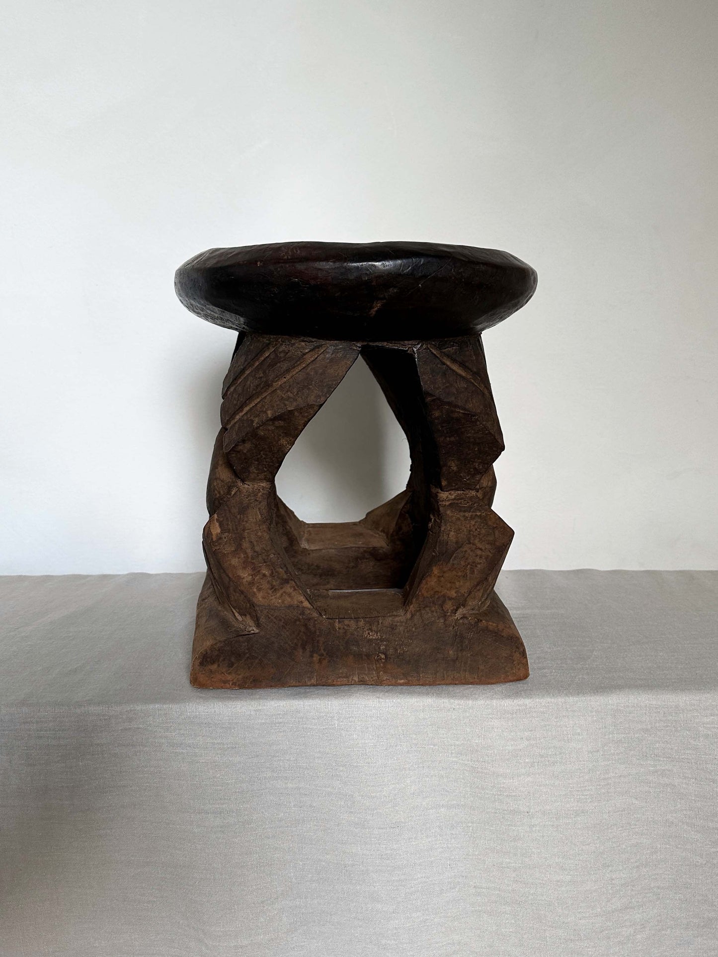 an antique tribal stool with concaved seat