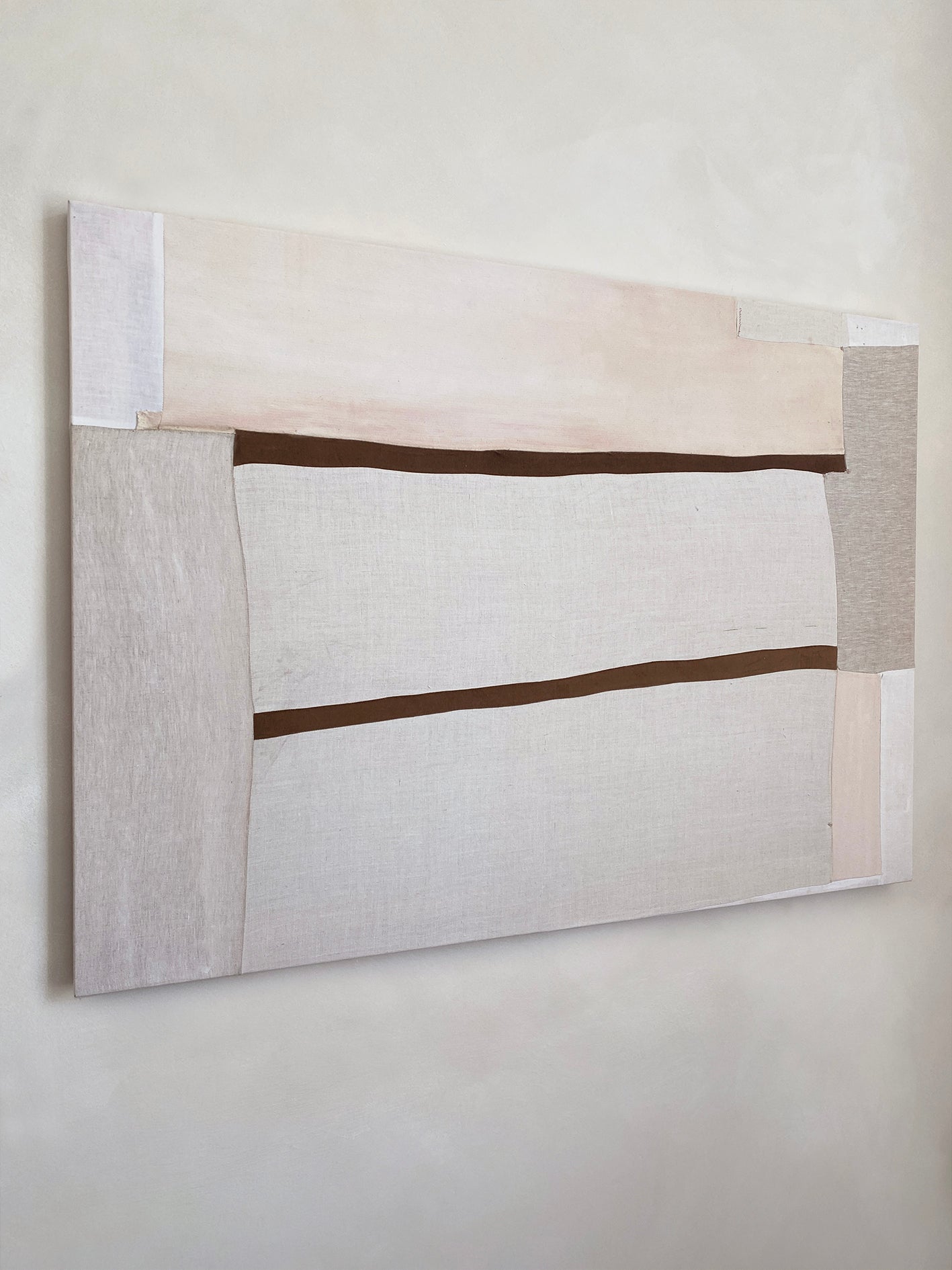 a large abstract artwork with neutral fabric painterly elements and two strips of brown velvet
