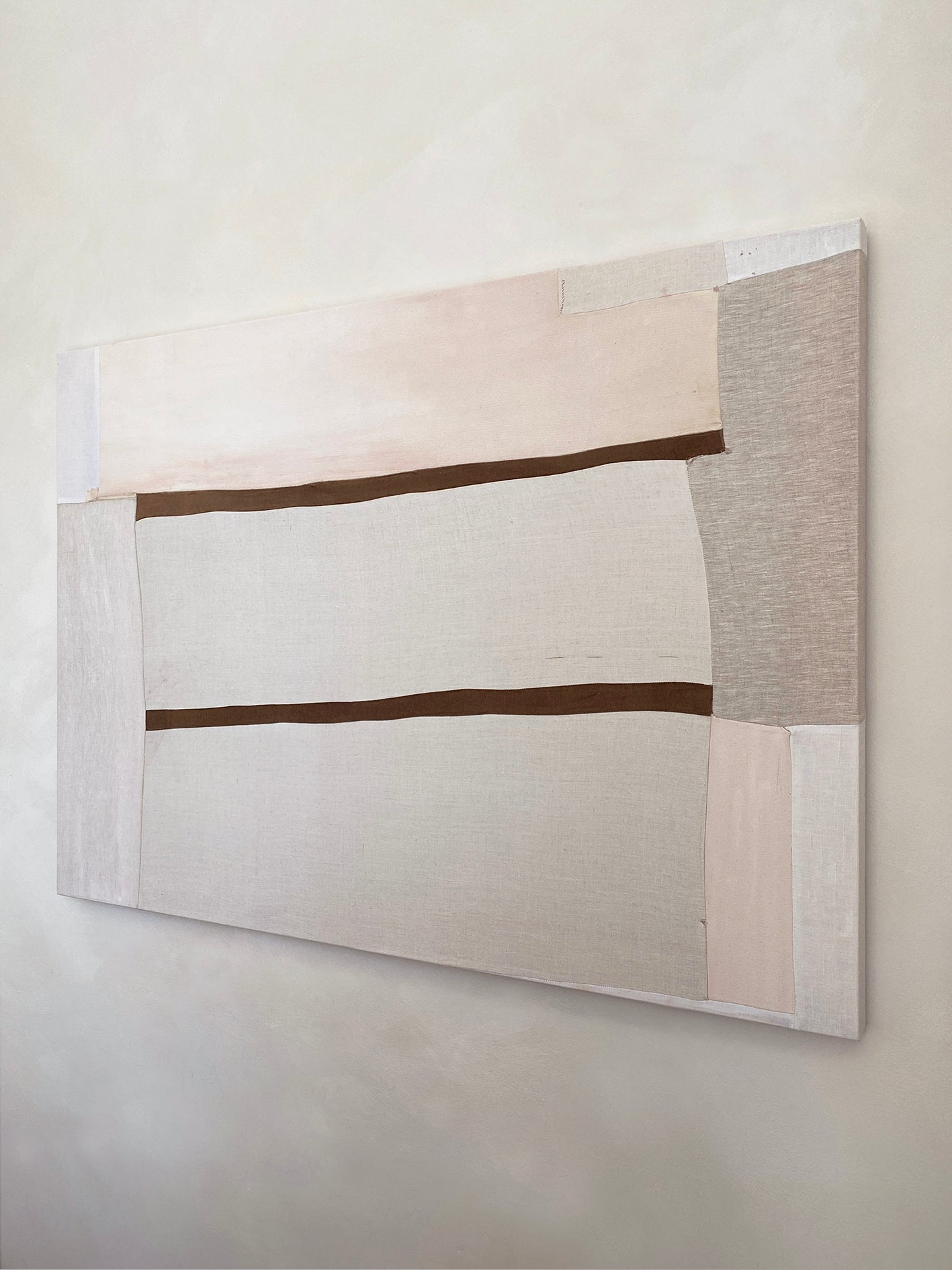 a large abstract artwork with neutral fabric painterly elements and two strips of brown velvet