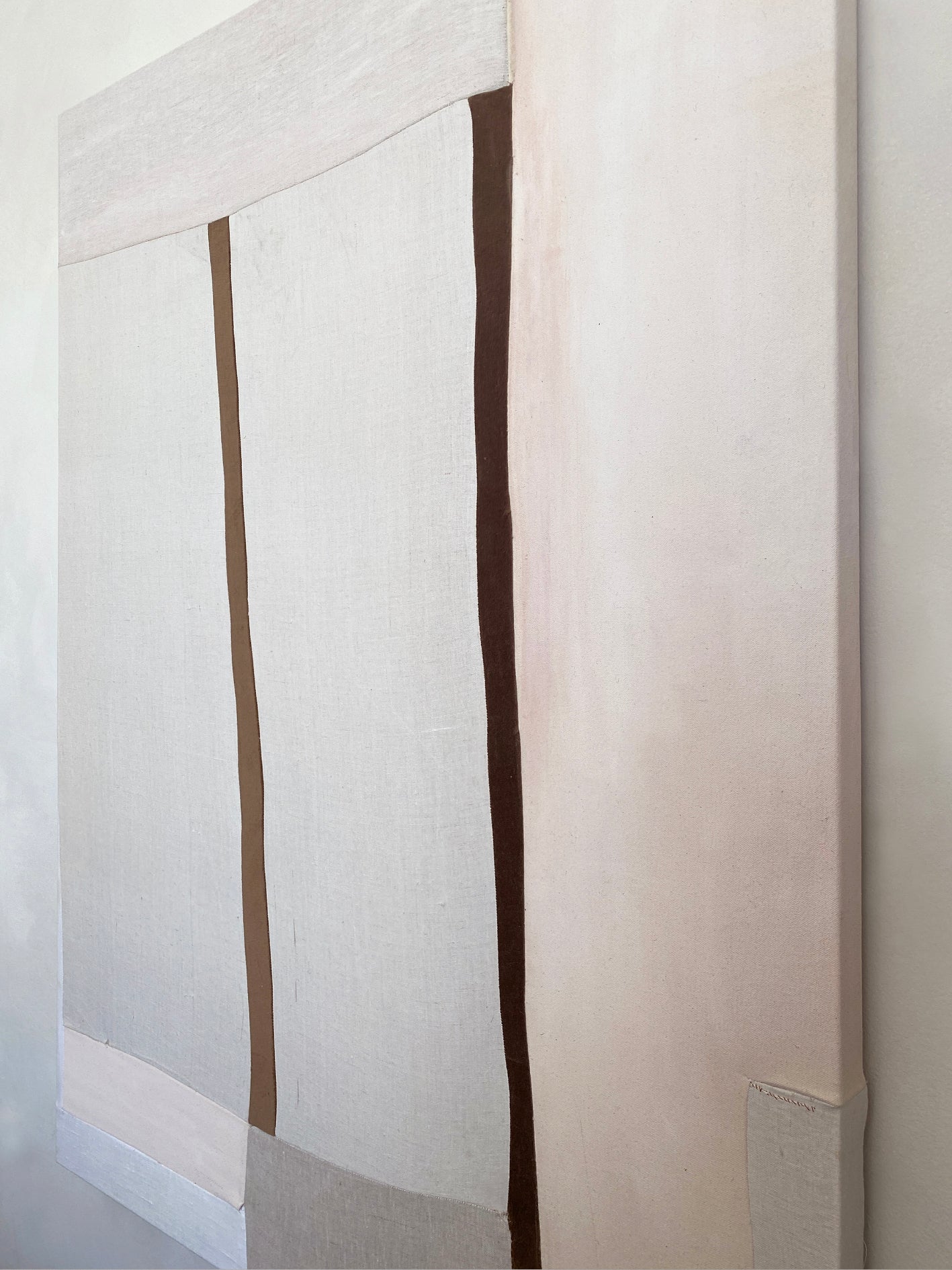 a large abstract artwork with neutral fabric painterly elements and two strips of brown velvet