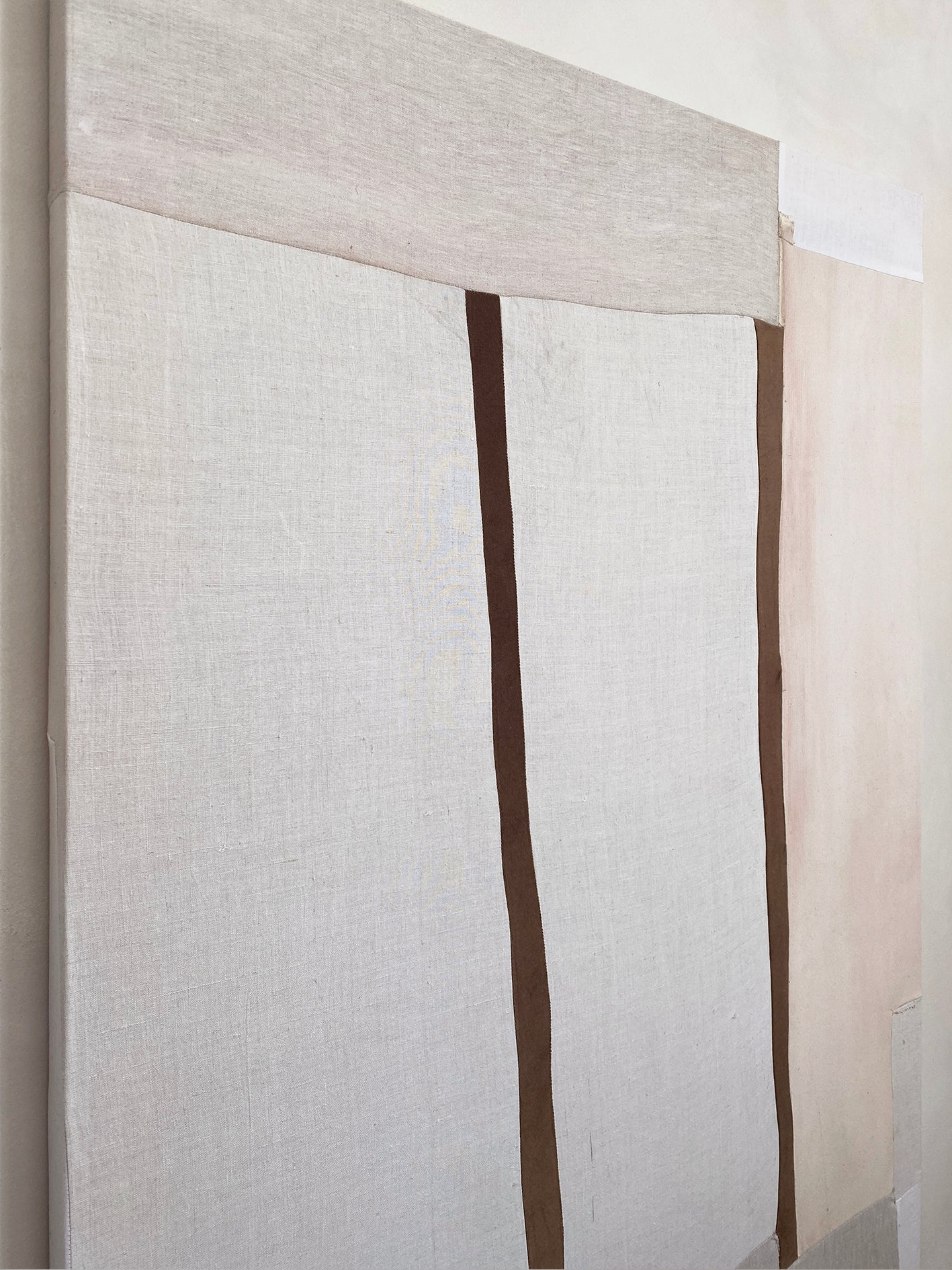 a large abstract artwork with neutral fabric painterly elements and two strips of brown velvet