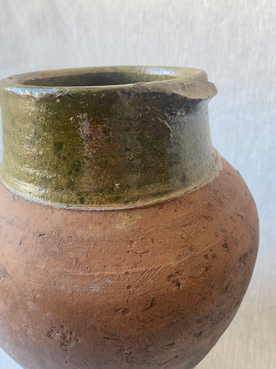 a large antique Turkish pot in terracotta with an olive green glaze