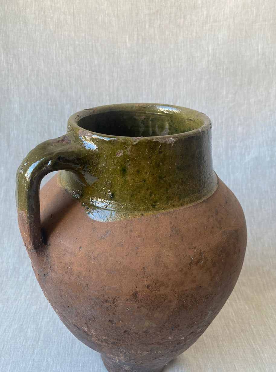 a large antique Turkish pot in terracotta with an olive green glaze