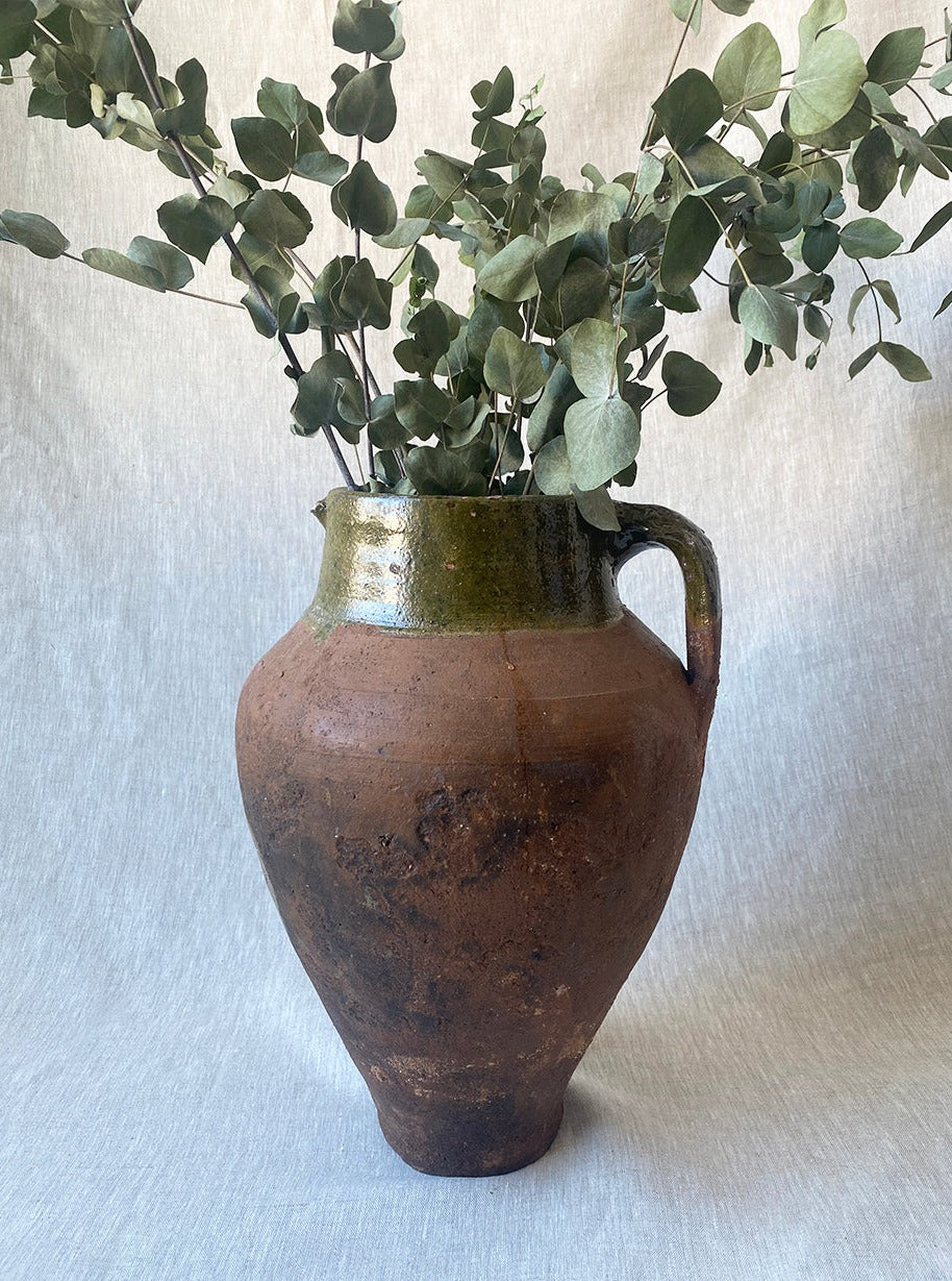 a large antique Turkish pot in terracotta with an olive green glaze