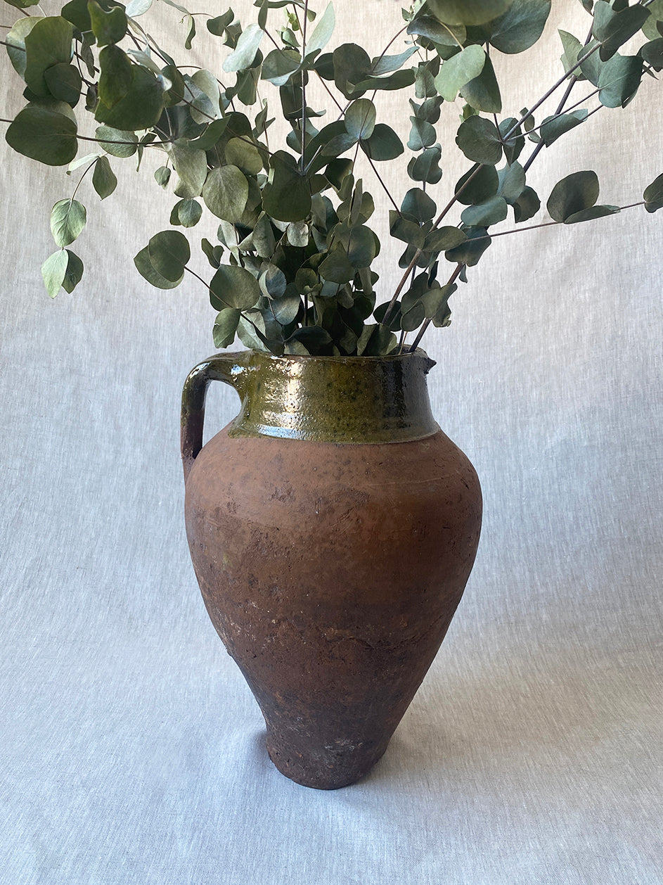 a large antique Turkish pot in terracotta with an olive green glaze