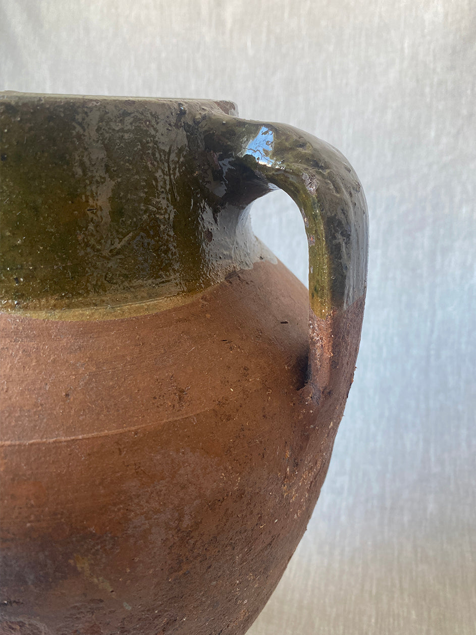 a large antique Turkish pot in terracotta with an olive green glaze