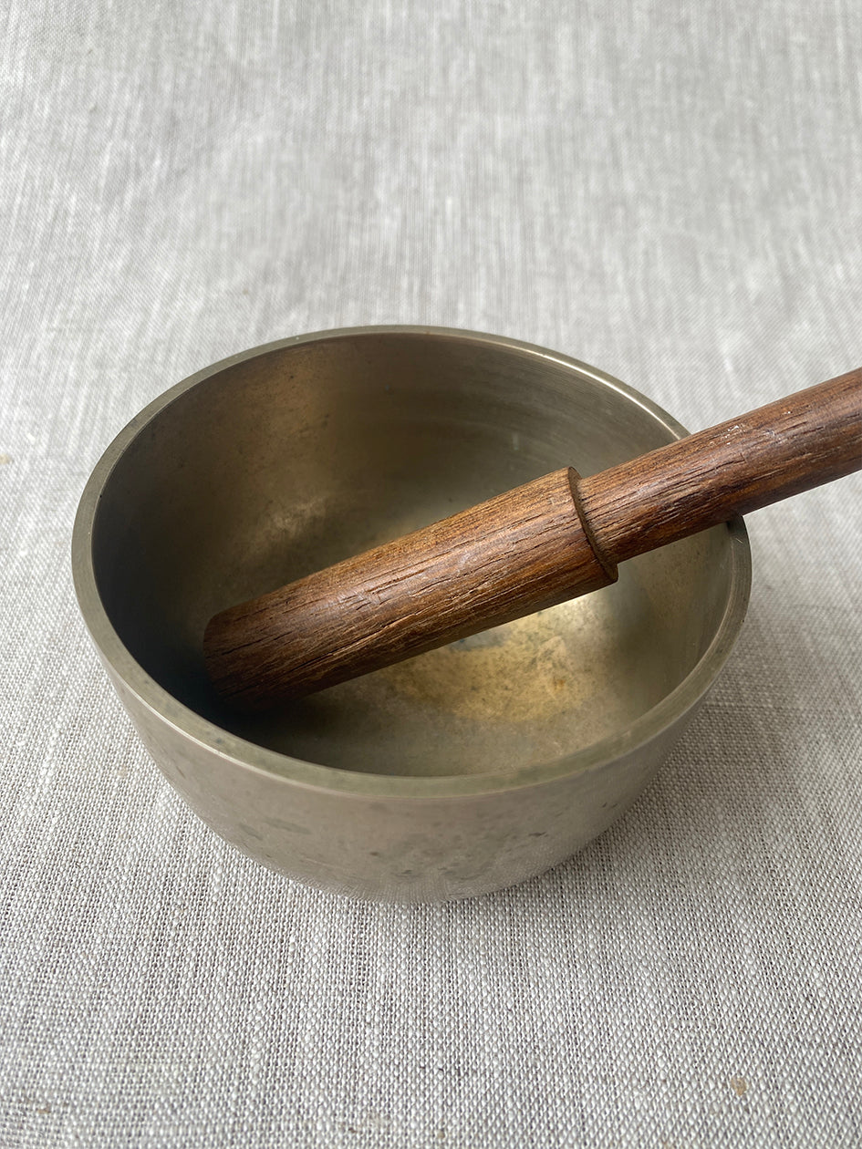 an antique meditation bowl with a small wooden striker