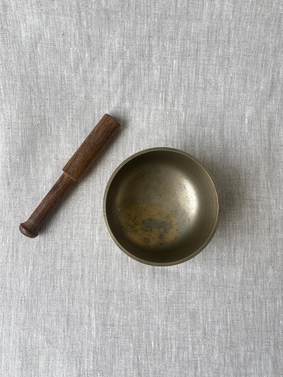 an antique meditation bowl with a small wooden striker