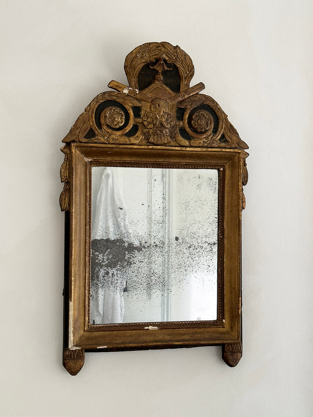 An antique French 18th-century Louis XVI-style mirror, decorated with tassels and laurel leaves in original gildwood.