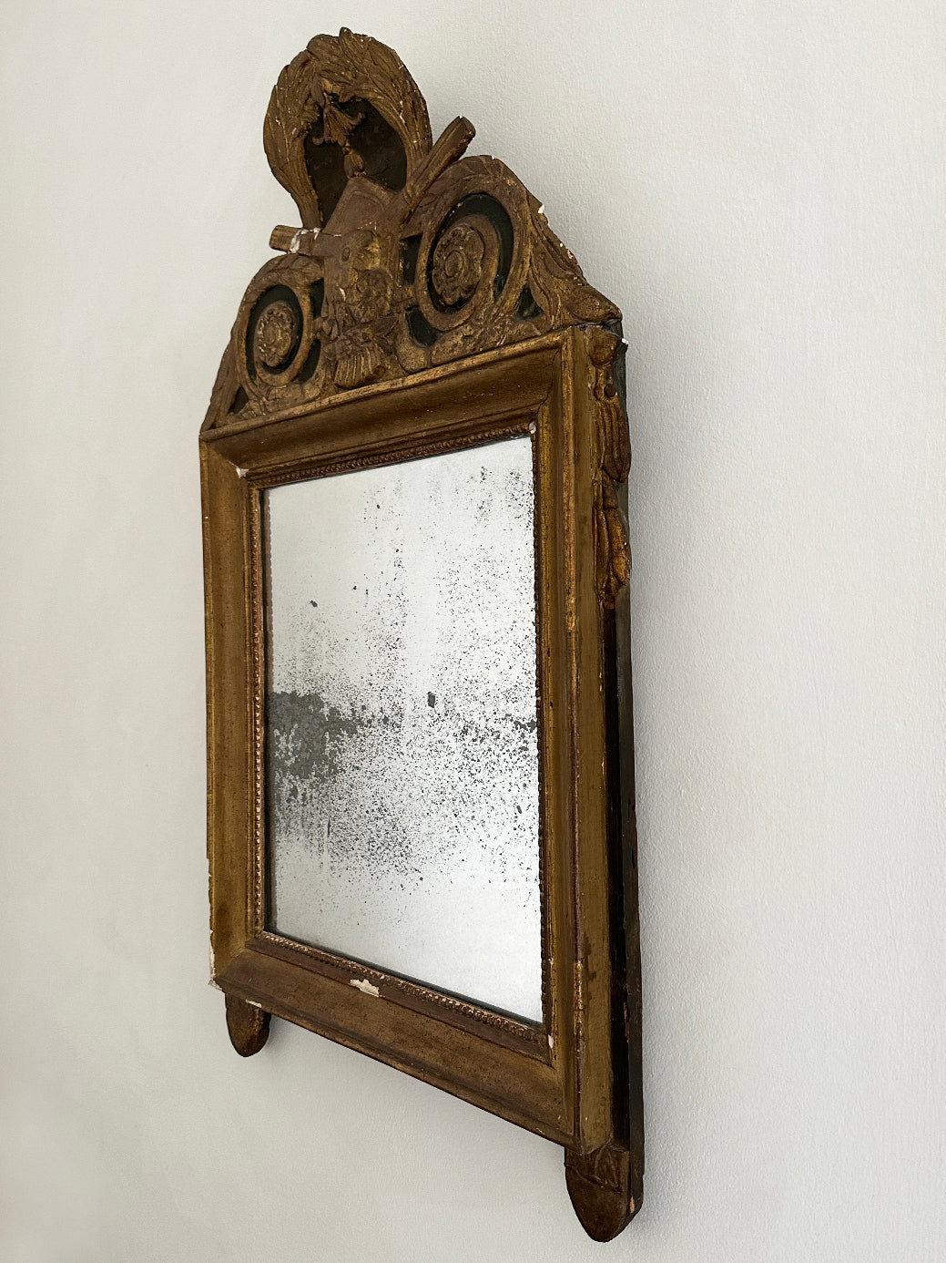 An antique French 18th-century Louis XVI-style mirror, decorated with tassels and laurel leaves in original gildwood.