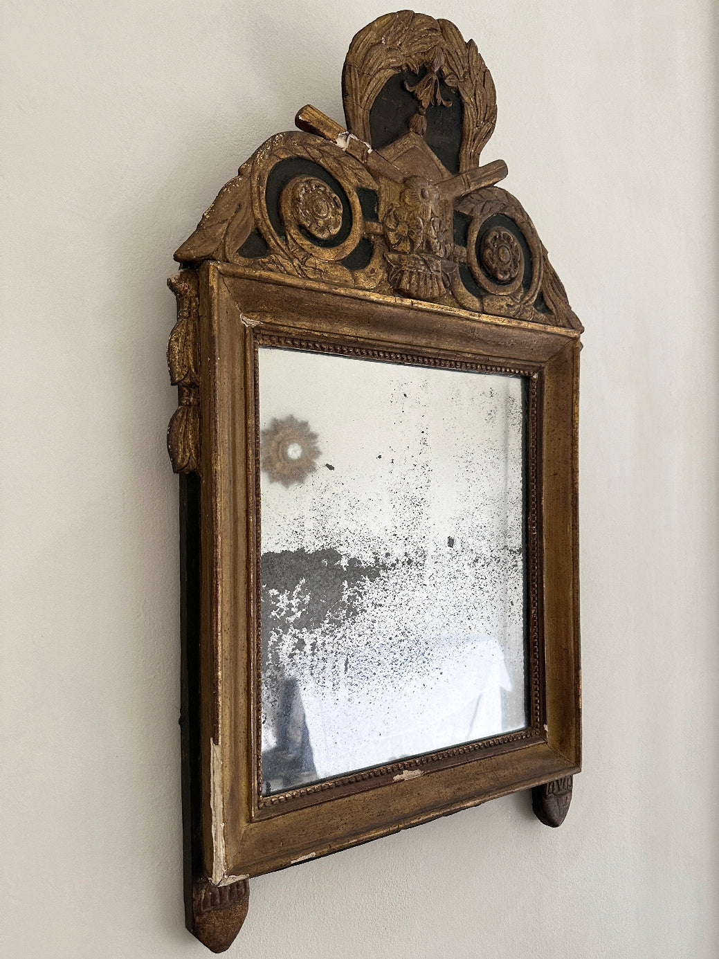 An antique French 18th-century Louis XVI-style mirror, decorated with tassels and laurel leaves in original gildwood.