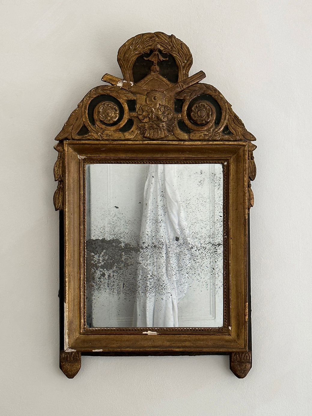 An antique French 18th-century Louis XVI-style mirror, decorated with tassels and laurel leaves in original gildwood.