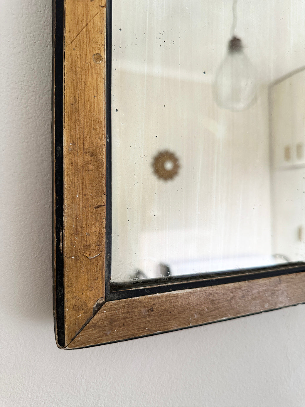 a small antique gentleman's shaving mirror in a natural wood and black frame with some light frosting