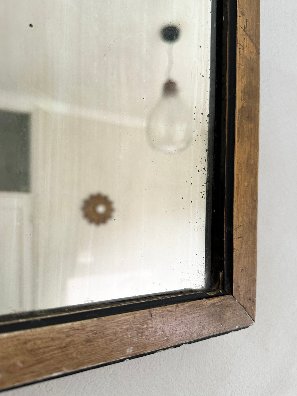 a small antique gentleman's shaving mirror in a natural wood and black frame with some light frosting