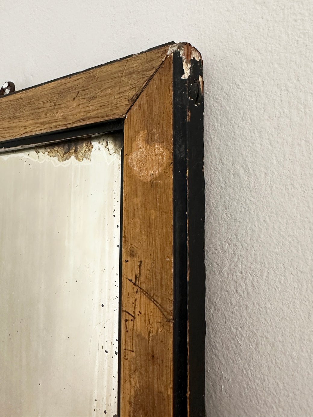 a small antique gentleman's shaving mirror in a natural wood and black frame with some light frosting