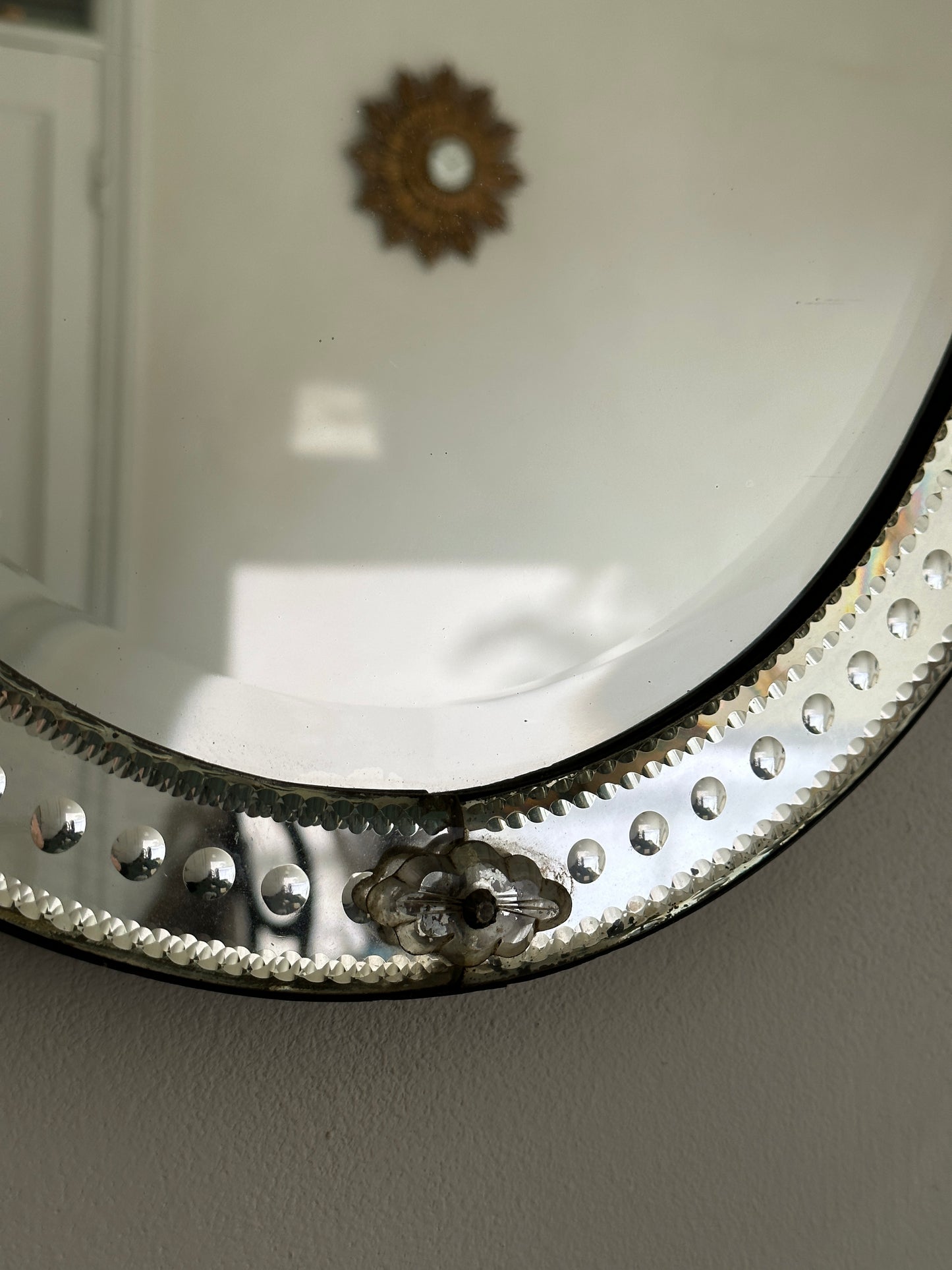 An early 20th-century Venetian mirror in etched glass with bevelled edges and an ornate bow cartouche.