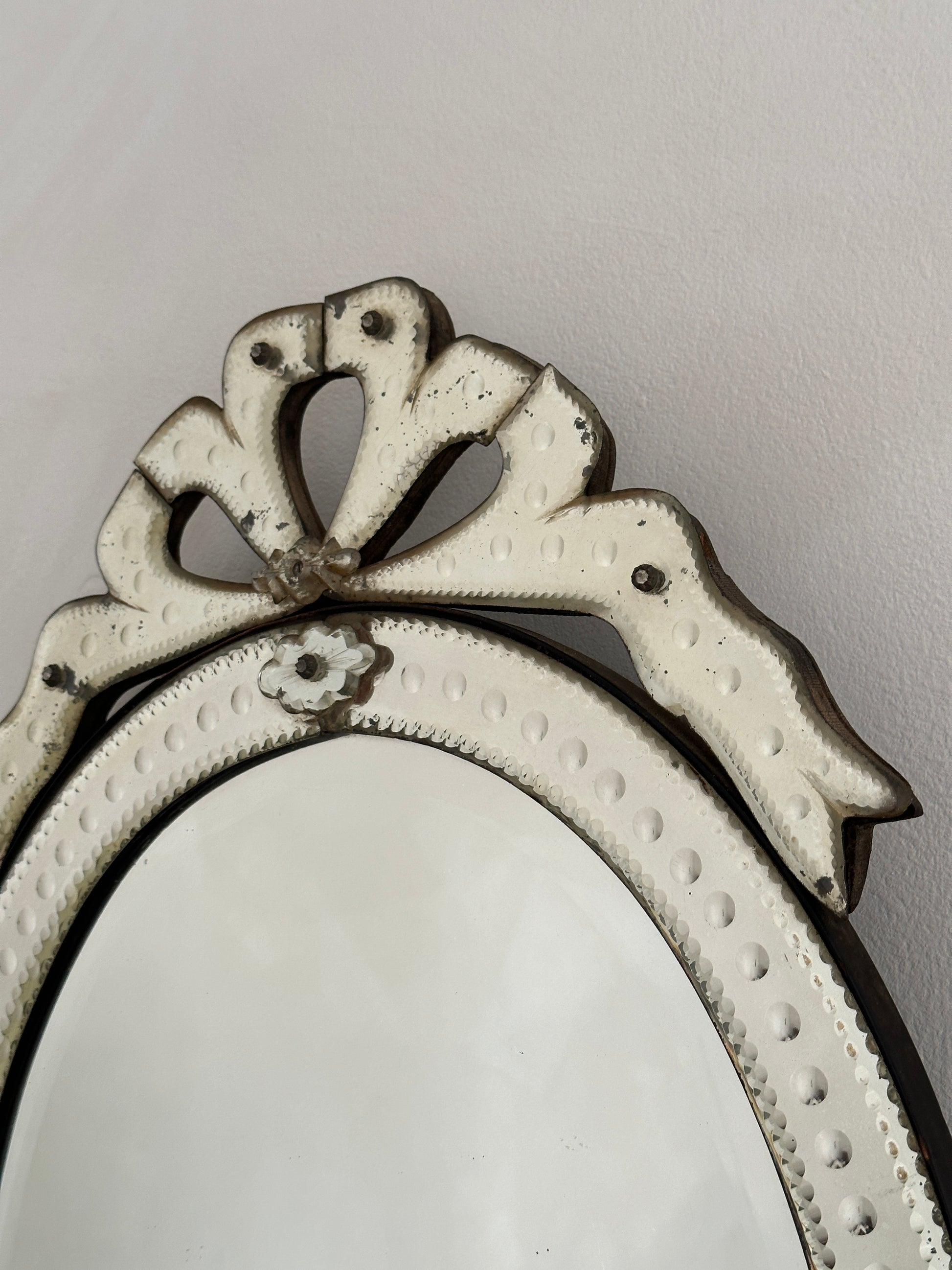 An early 20th-century Venetian mirror in etched glass with bevelled edges and an ornate bow cartouche.