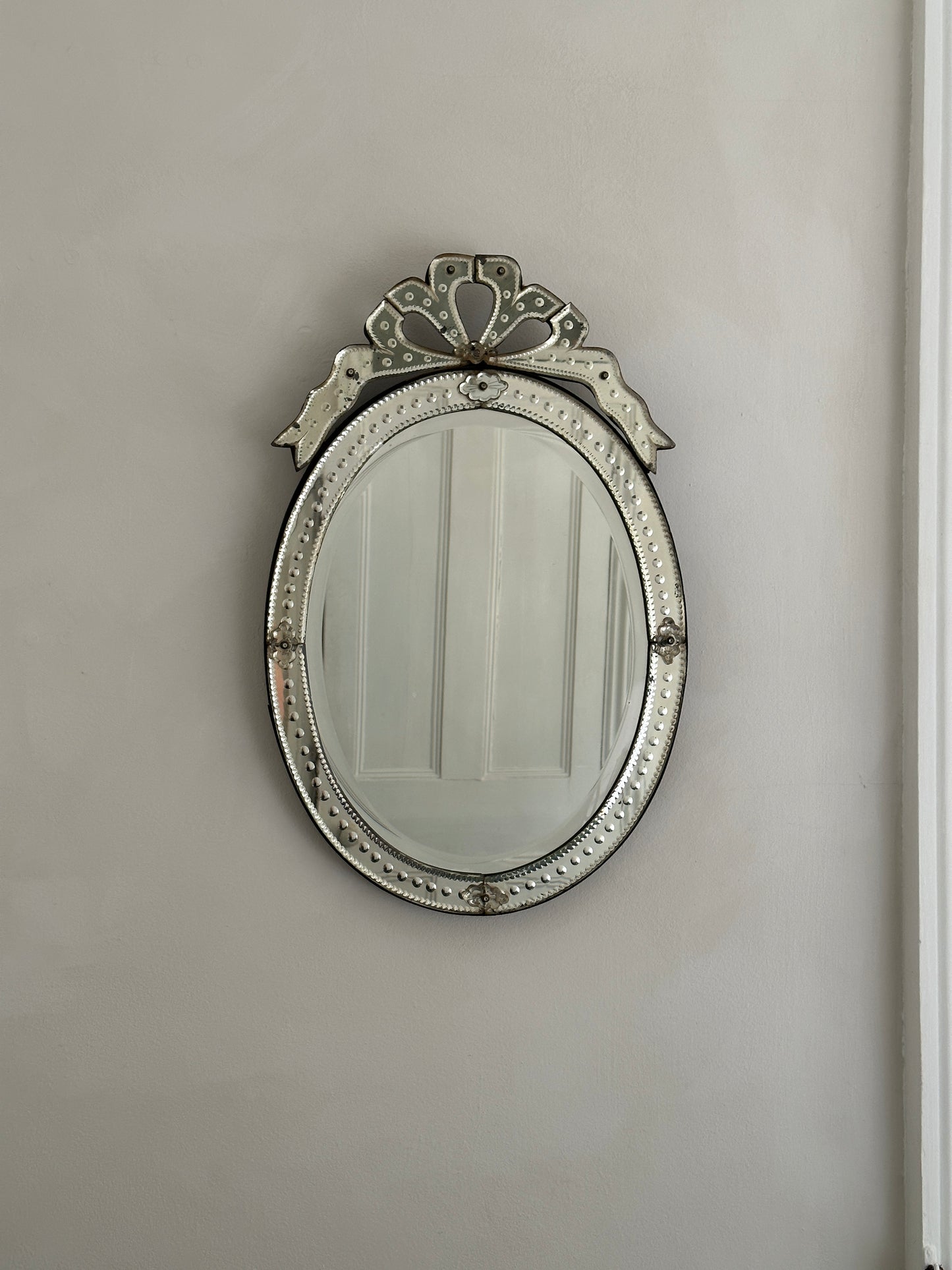 An early 20th-century Venetian mirror in etched glass with bevelled edges and an ornate bow cartouche.