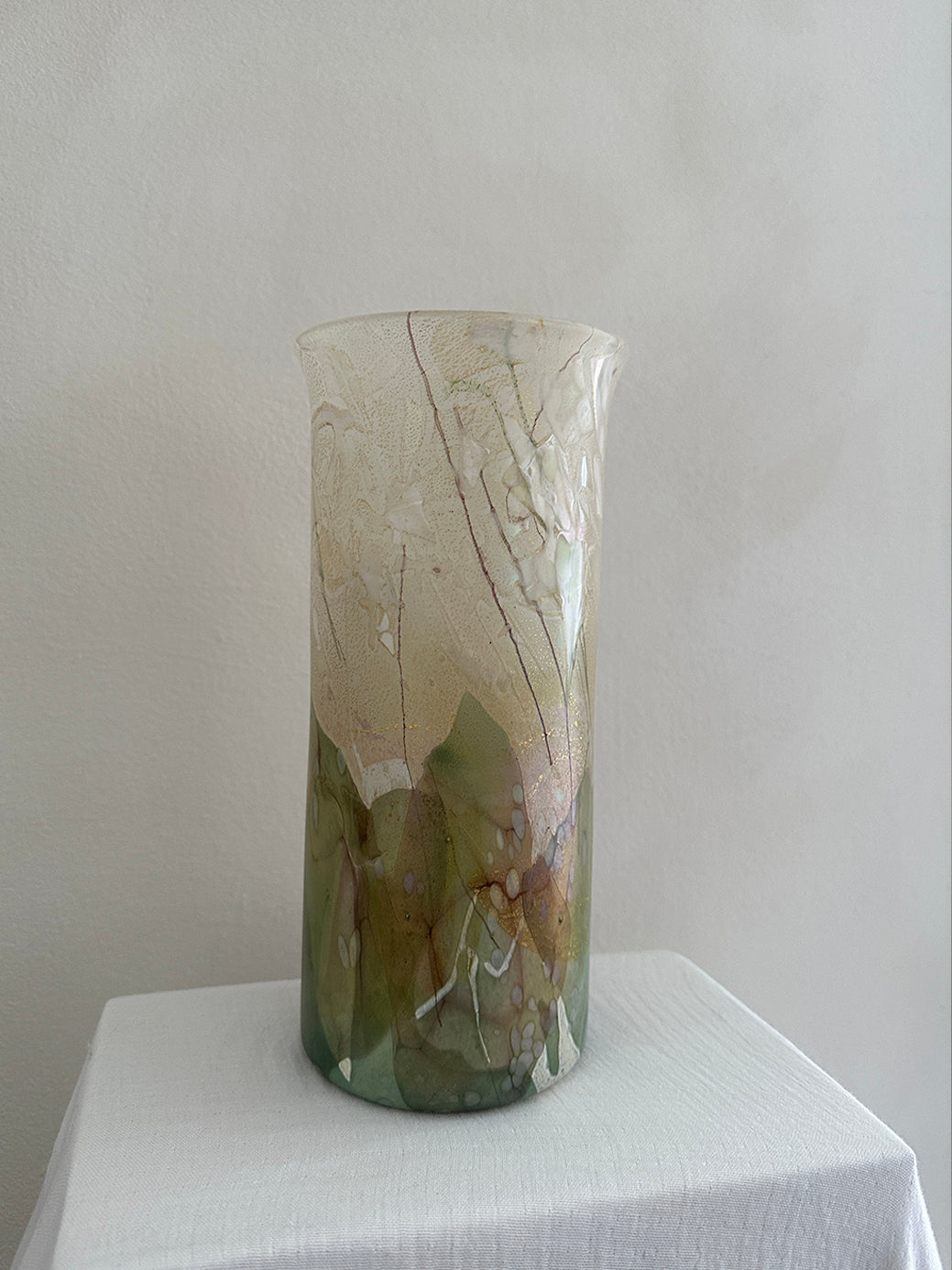 a vintage glass cylinder vase made by isle of wight studios. In pastel tones with an iridescent finish