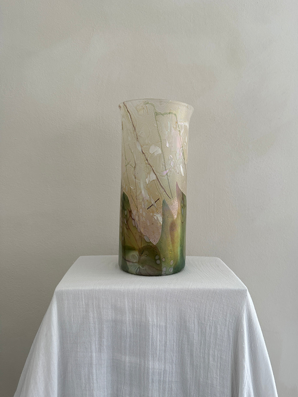 a vintage glass cylinder vase made by isle of wight studios. In pastel tones with an iridescent finish