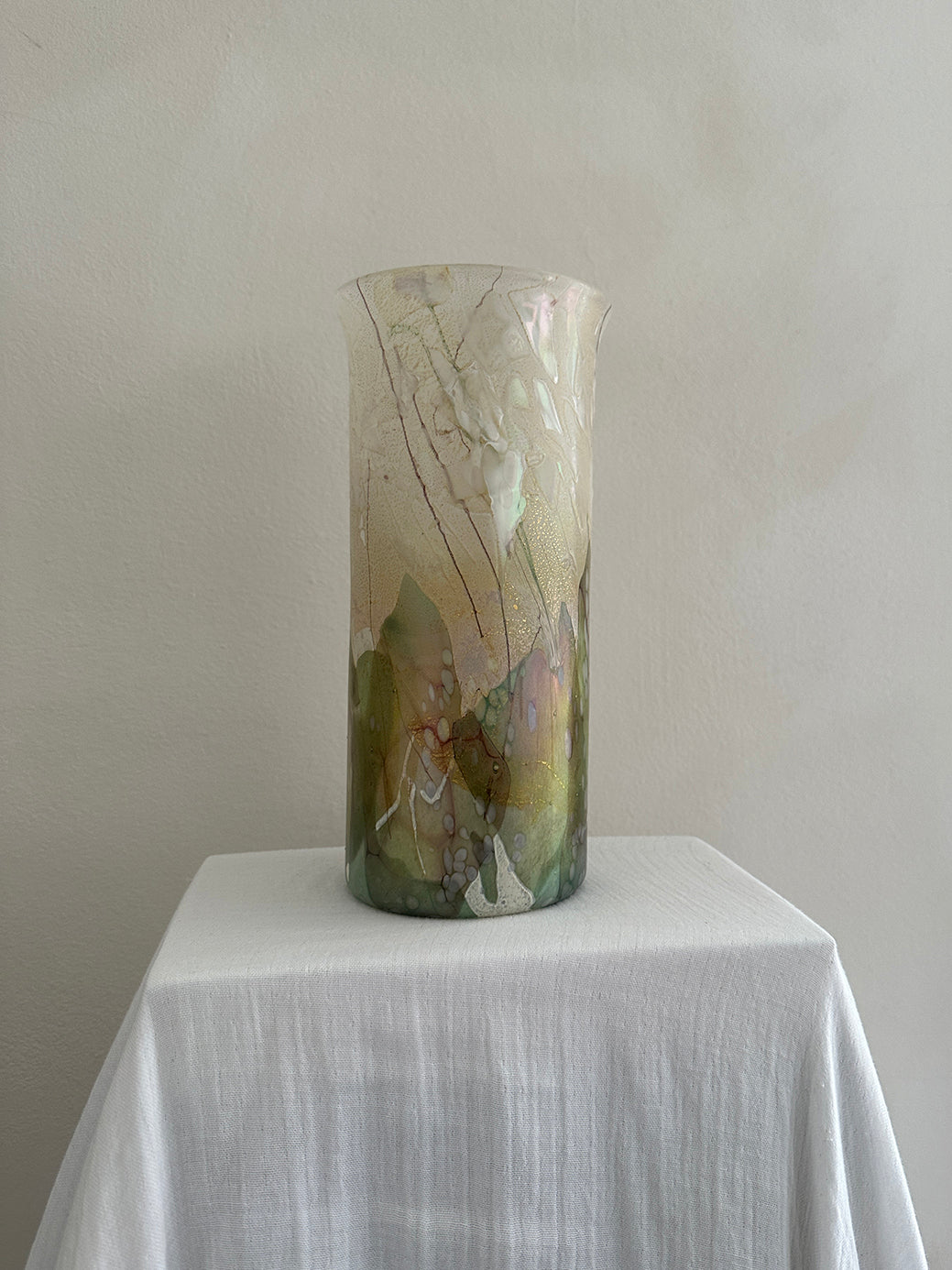 a vintage glass cylinder vase made by isle of wight studios. In pastel tones with an iridescent finish