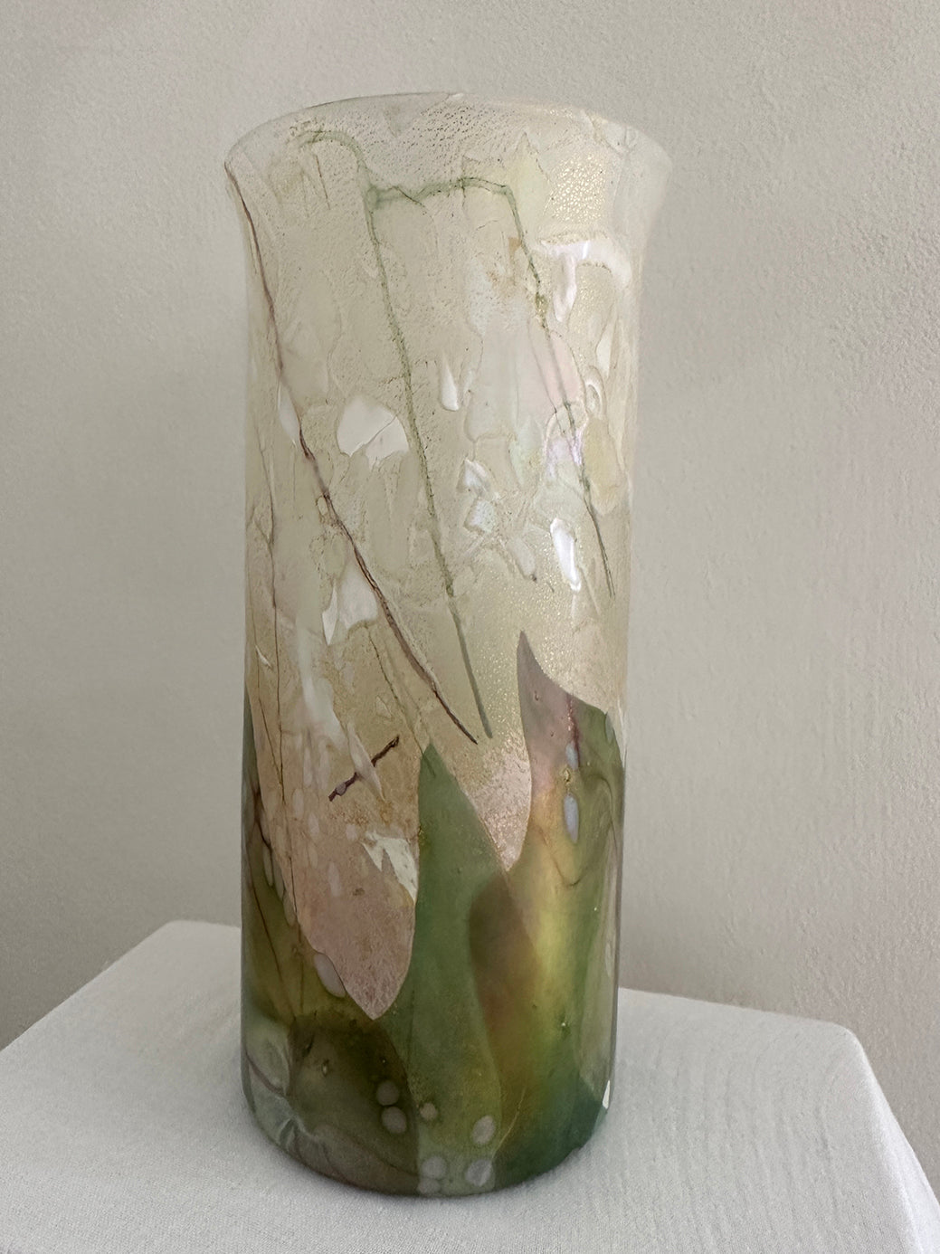 a vintage glass cylinder vase made by isle of wight studios. In pastel tones with an iridescent finish