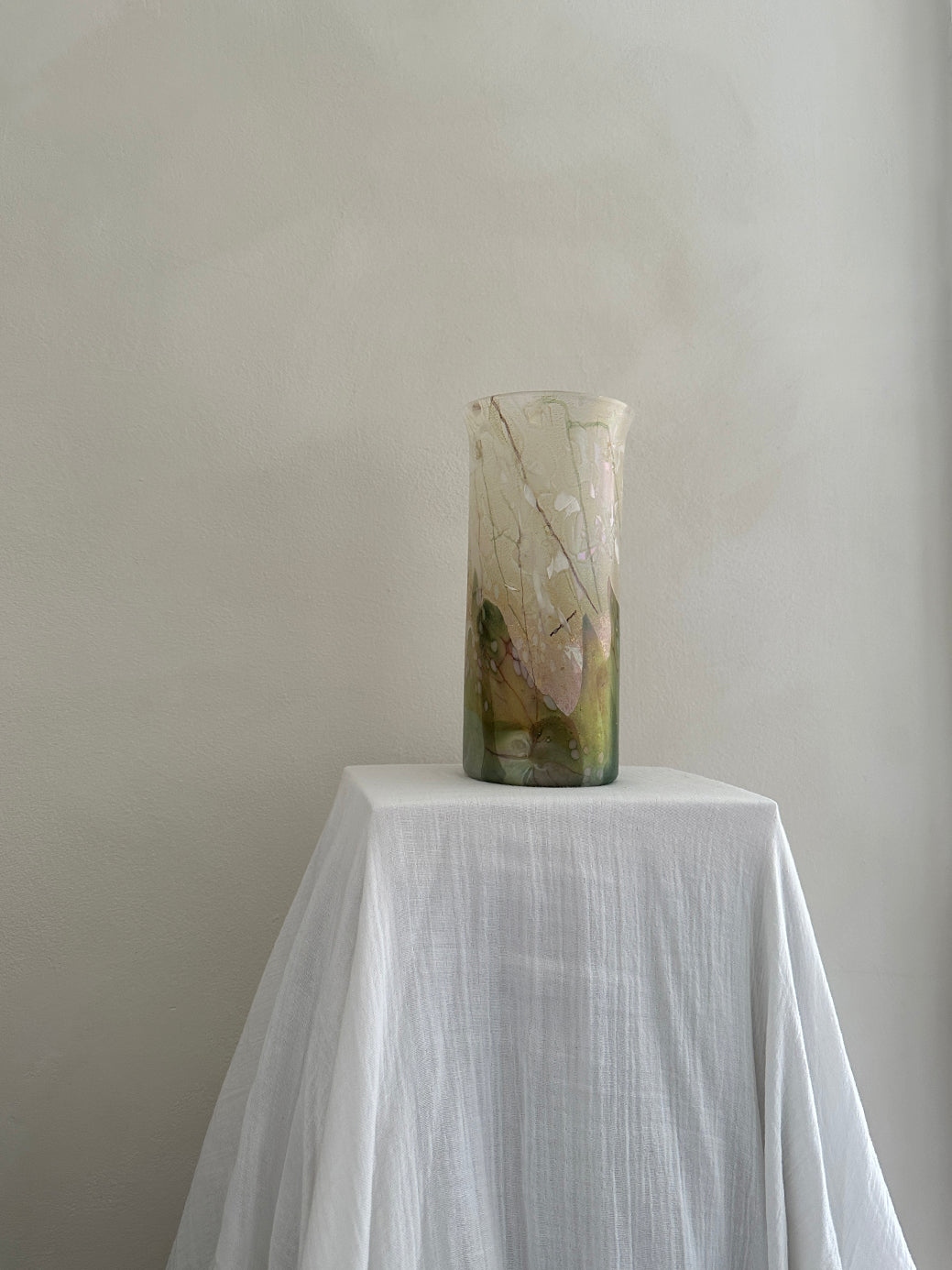 a vintage glass cylinder vase made by isle of wight studios. In pastel tones with an iridescent finish