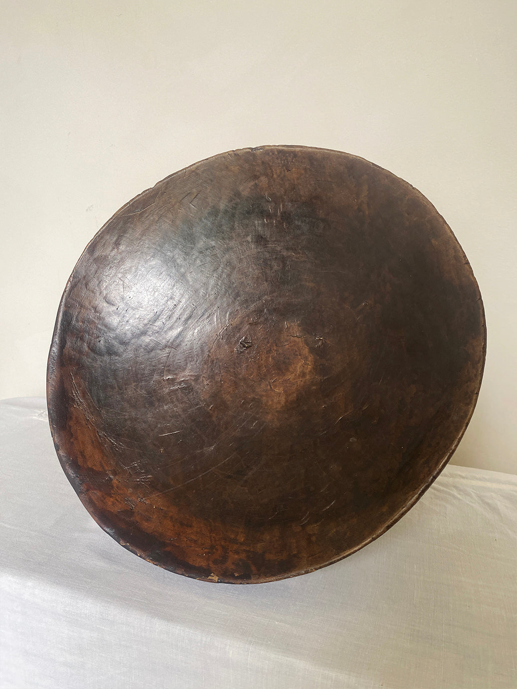 an antique hand-carved wooden stool with three sculptural legs and a round concave seat