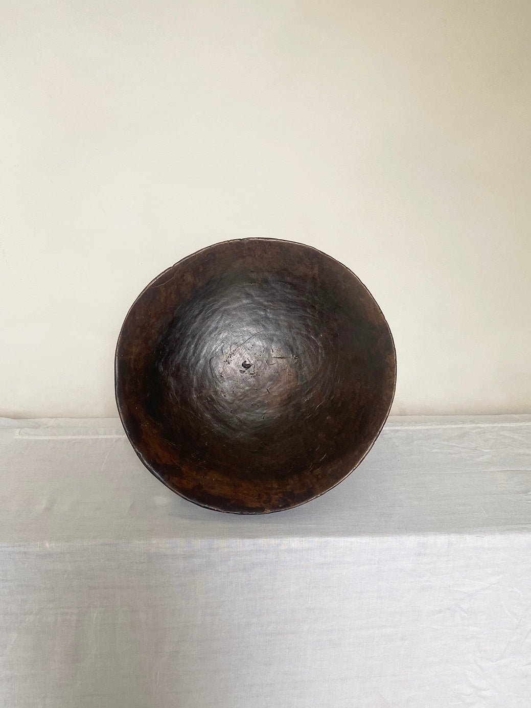 an antique hand-carved wooden stool with three sculptural legs and a round concave seat