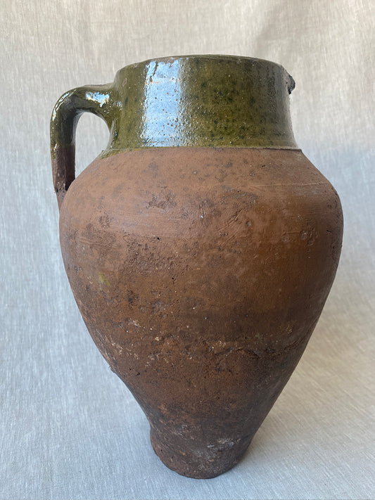 a large antique Turkish pot in terracotta with an olive green glaze