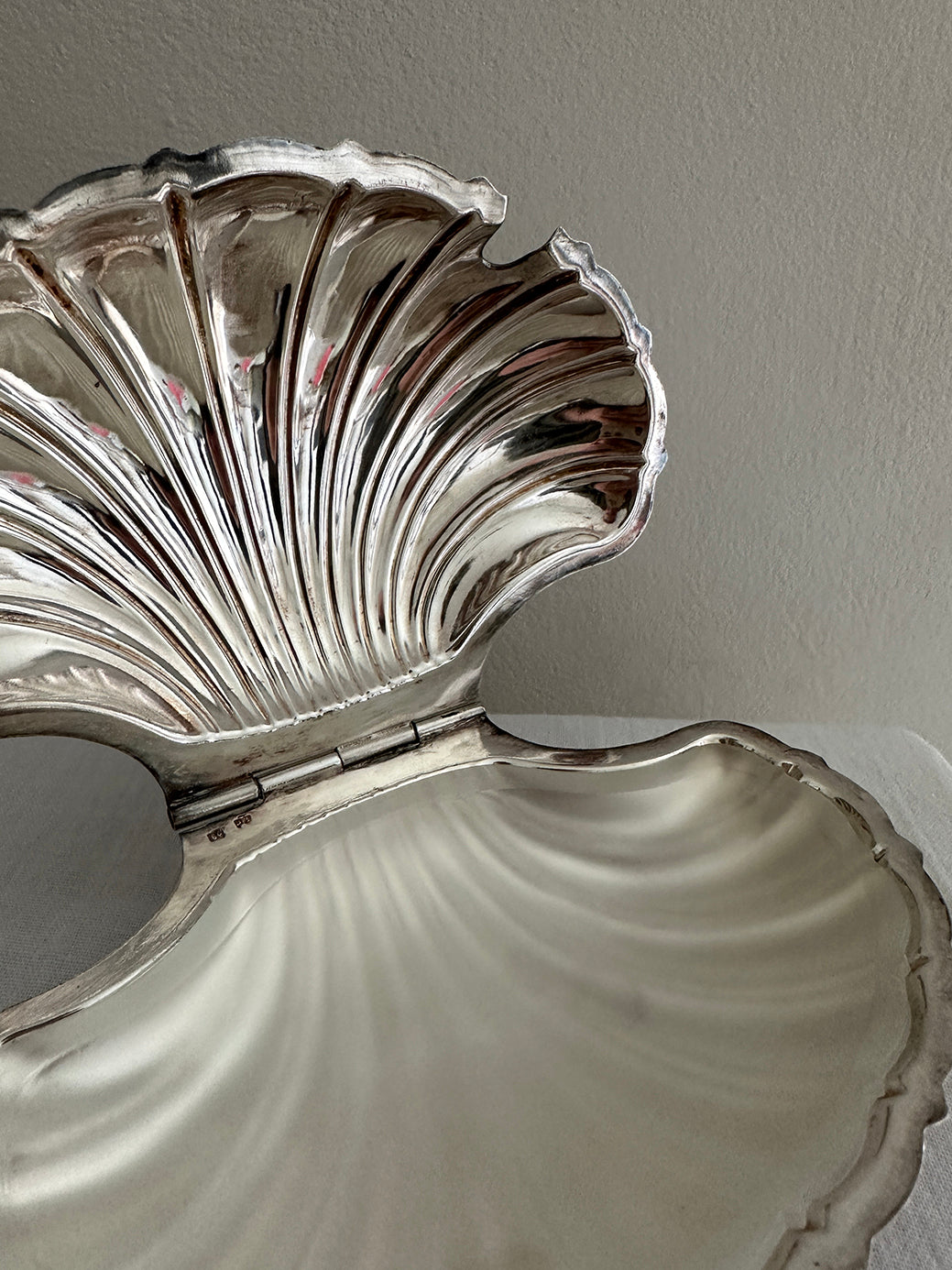 a victorian silver plated caviar dish in the shape of a clamshell, with silver feet and a glass insert