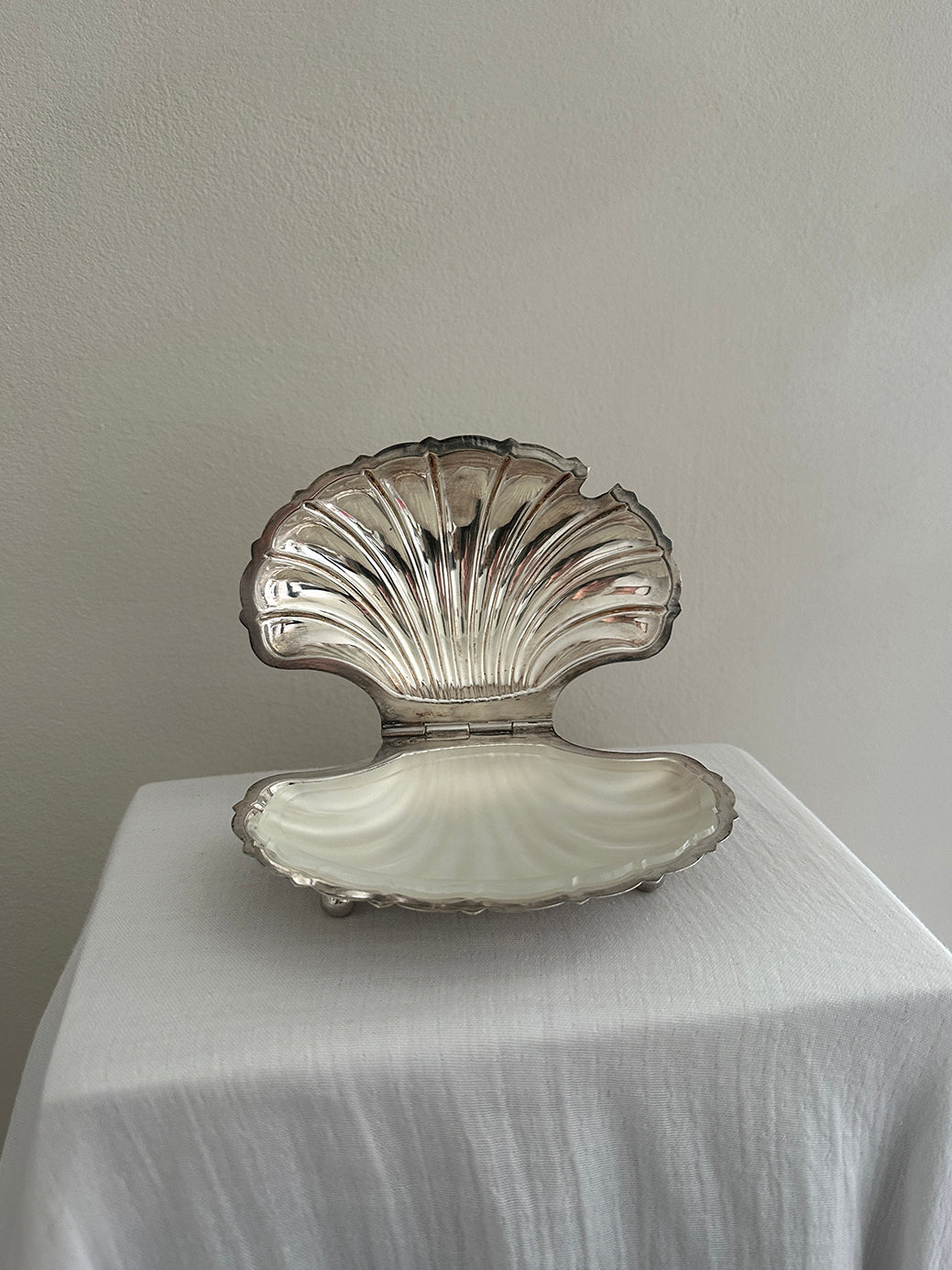 a victorian silver plated caviar dish in the shape of a clamshell, with silver feet and a glass insert