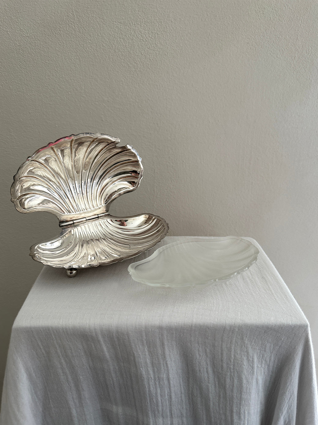 a victorian silver plated caviar dish in the shape of a clamshell, with silver feet and a glass insert