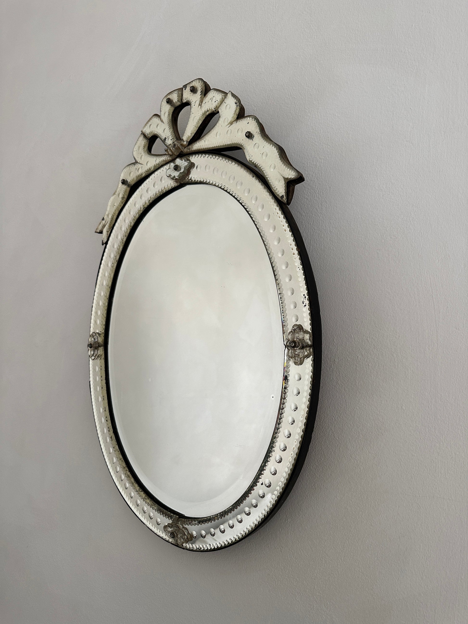 An early 20th-century Venetian mirror in etched glass with bevelled edges and an ornate bow cartouche.