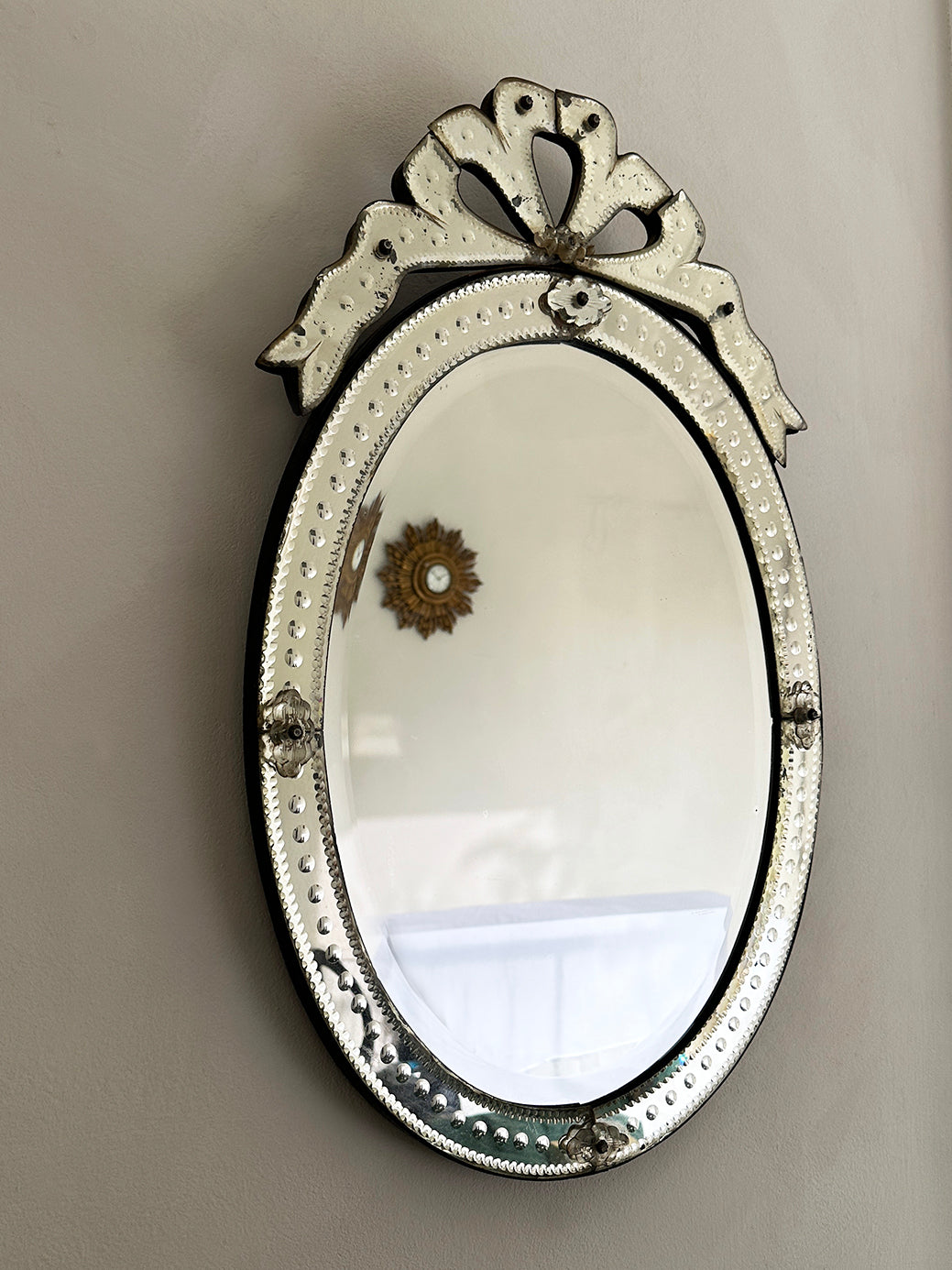 An early 20th-century Venetian mirror in etched glass with bevelled edges and an ornate bow cartouche.