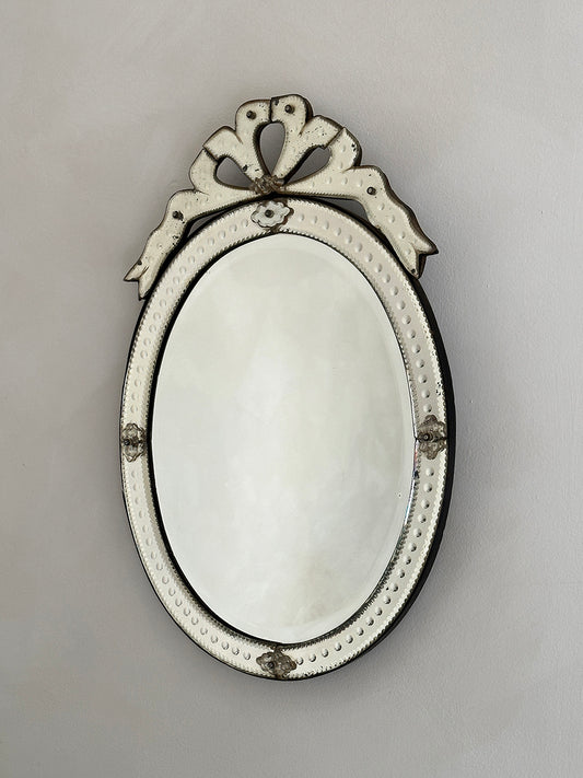 An early 20th-century Venetian mirror in etched glass with bevelled edges and an ornate bow cartouche.