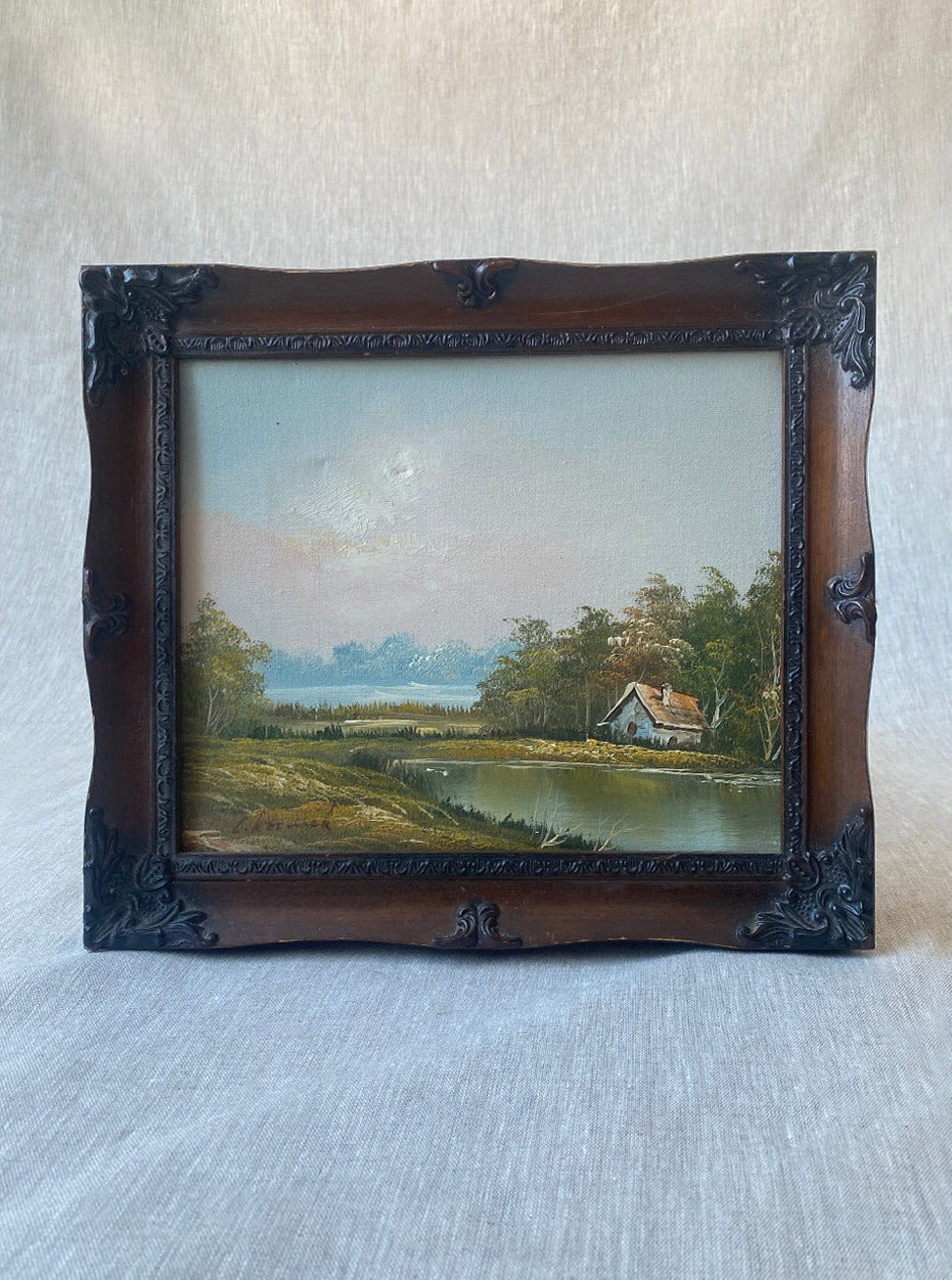 a vintage oil waterscape painting in an ornate wooden frame