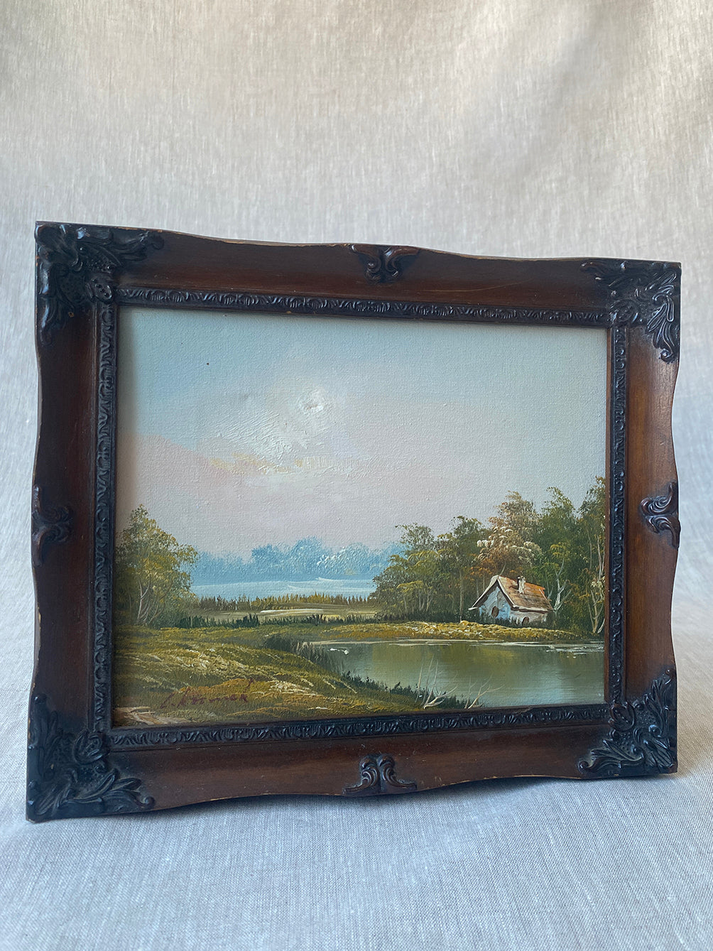 a vintage oil waterscape painting in an ornate wooden frame