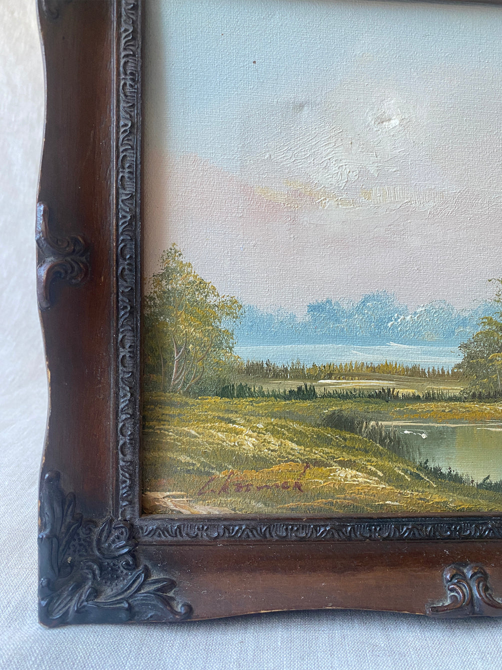 a vintage oil waterscape painting in an ornate wooden frame