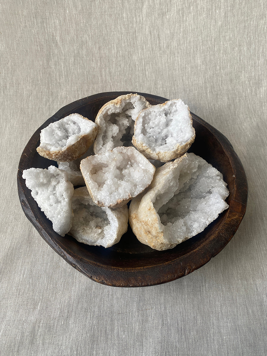 a selection of quartz geode crystals in a vintage carved African bowl